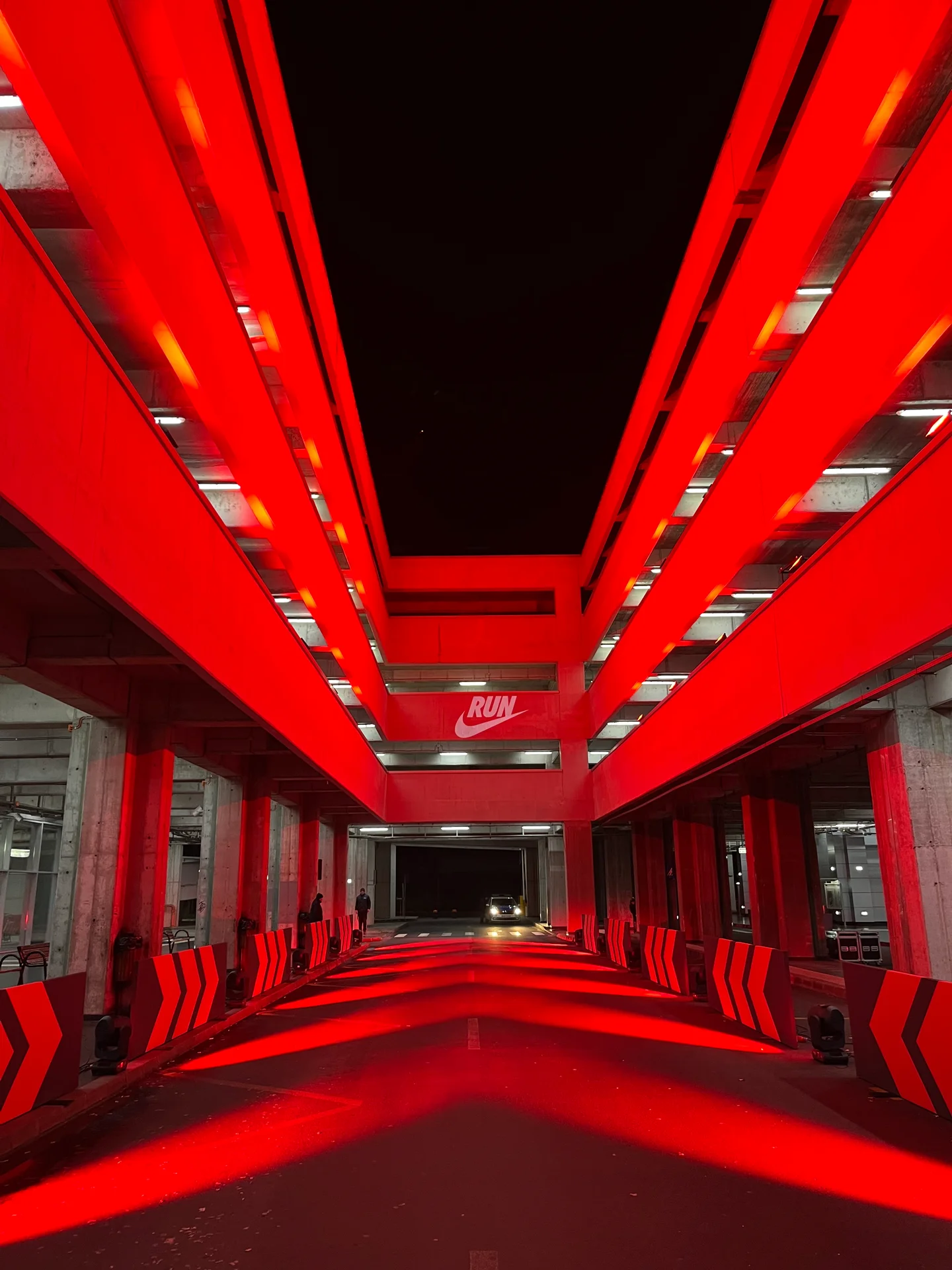 Red spotlights and directional barriers lining the Nike Midnight Run course beneath a Nike Run projection
